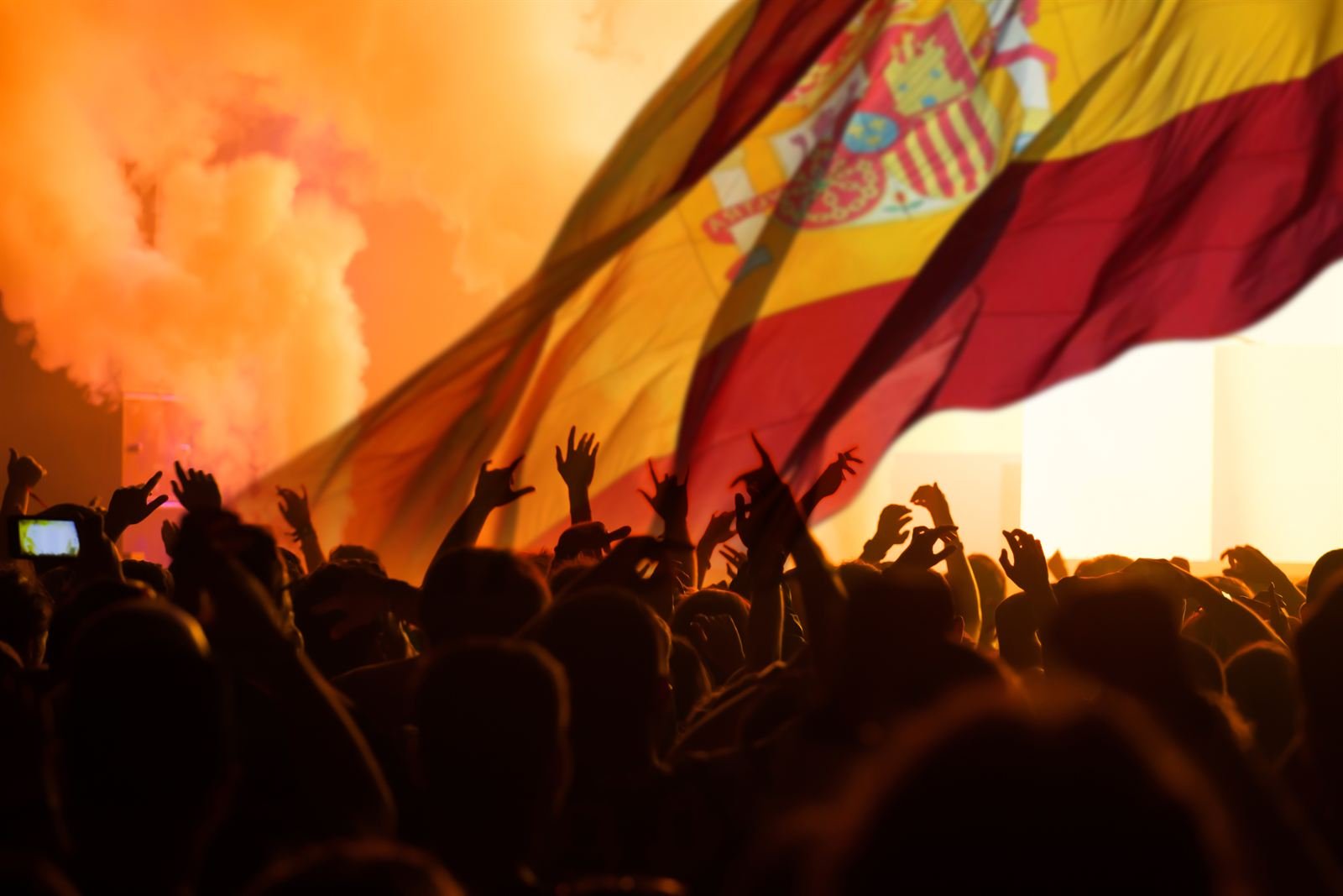 A Spanish flag waving above a cheering crowd