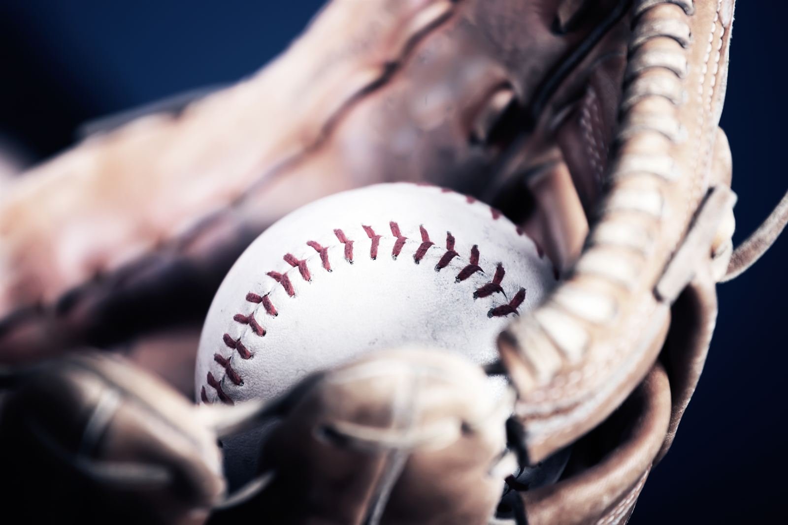 A baseball resting in a leather glove